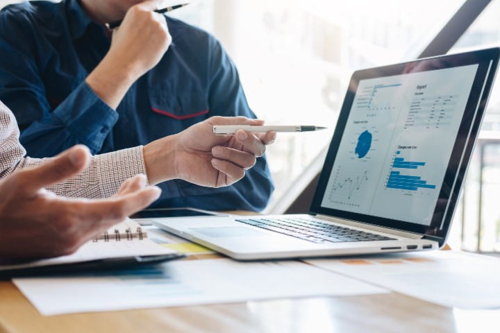marketing professionals discussing data insights displayed on a laptop screen with graphs and charts