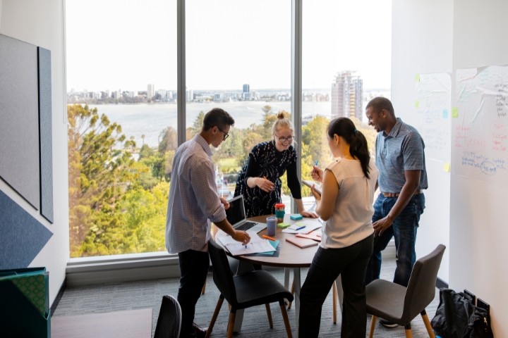 A group of marketing professionals working together on a project in a bright meeting room overlooking houston city skyline