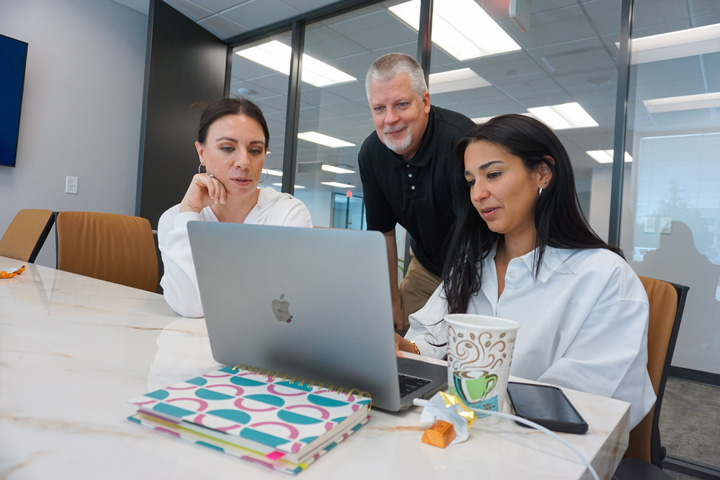 Marketing professionals reviewing a campaign strategy on a laptop during a team meeting