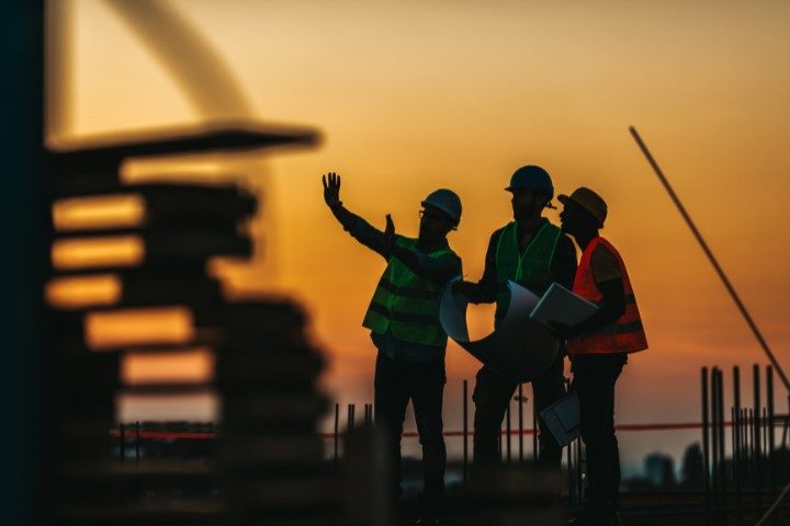 Contractors going over project details as the sun sets on a Houston construction site.