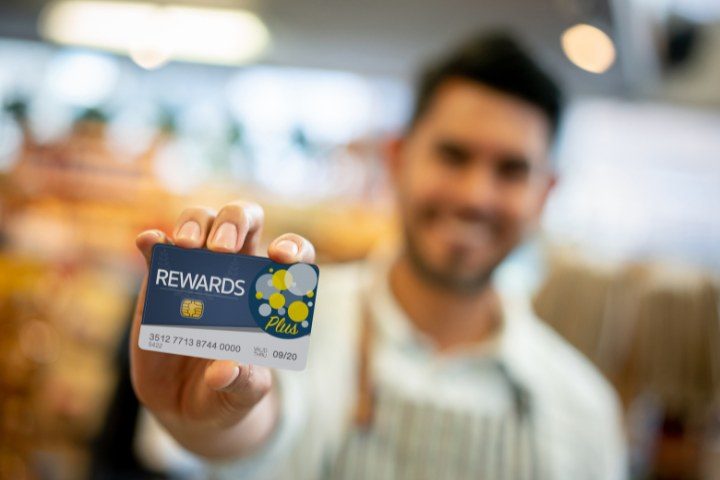 Smiling server holding up a loyalty rewards card to promote customer retention and repeat business